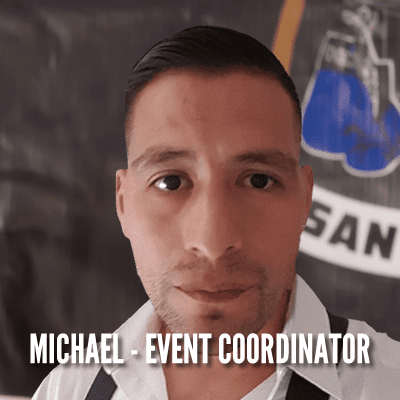 A man in front of a boxing ring with the words michael-event coordinator below him.