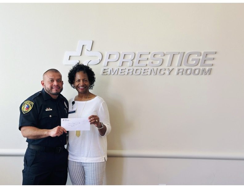 A woman and man holding a paper in front of a sign.