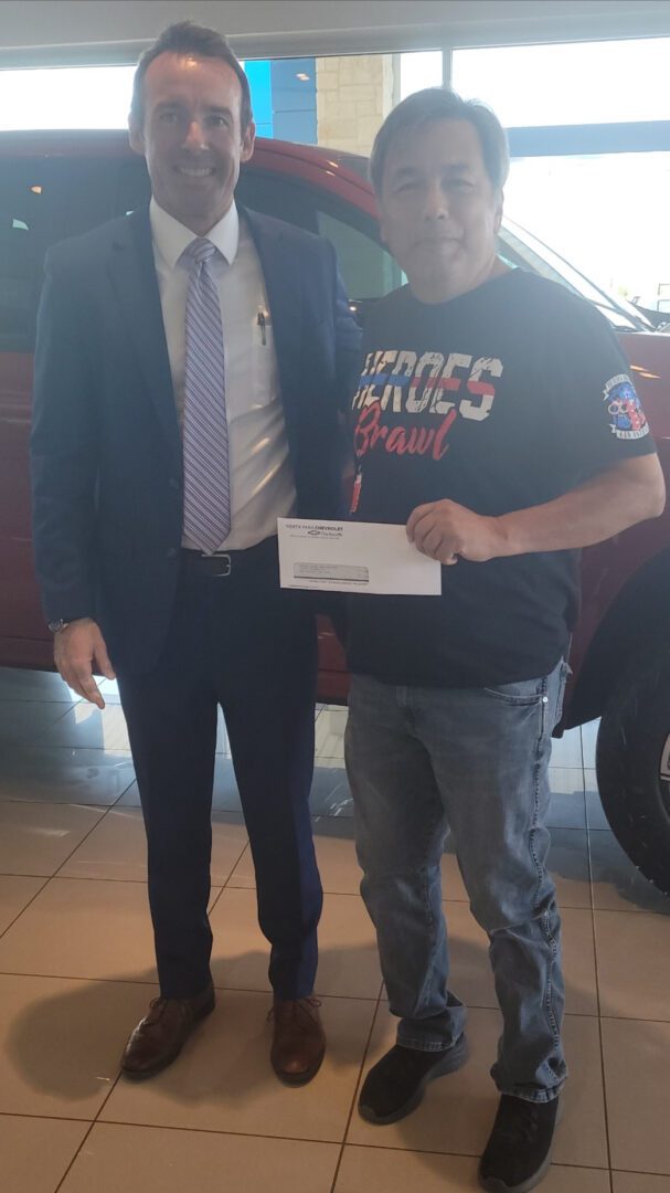 A man standing next to another man holding a paper.